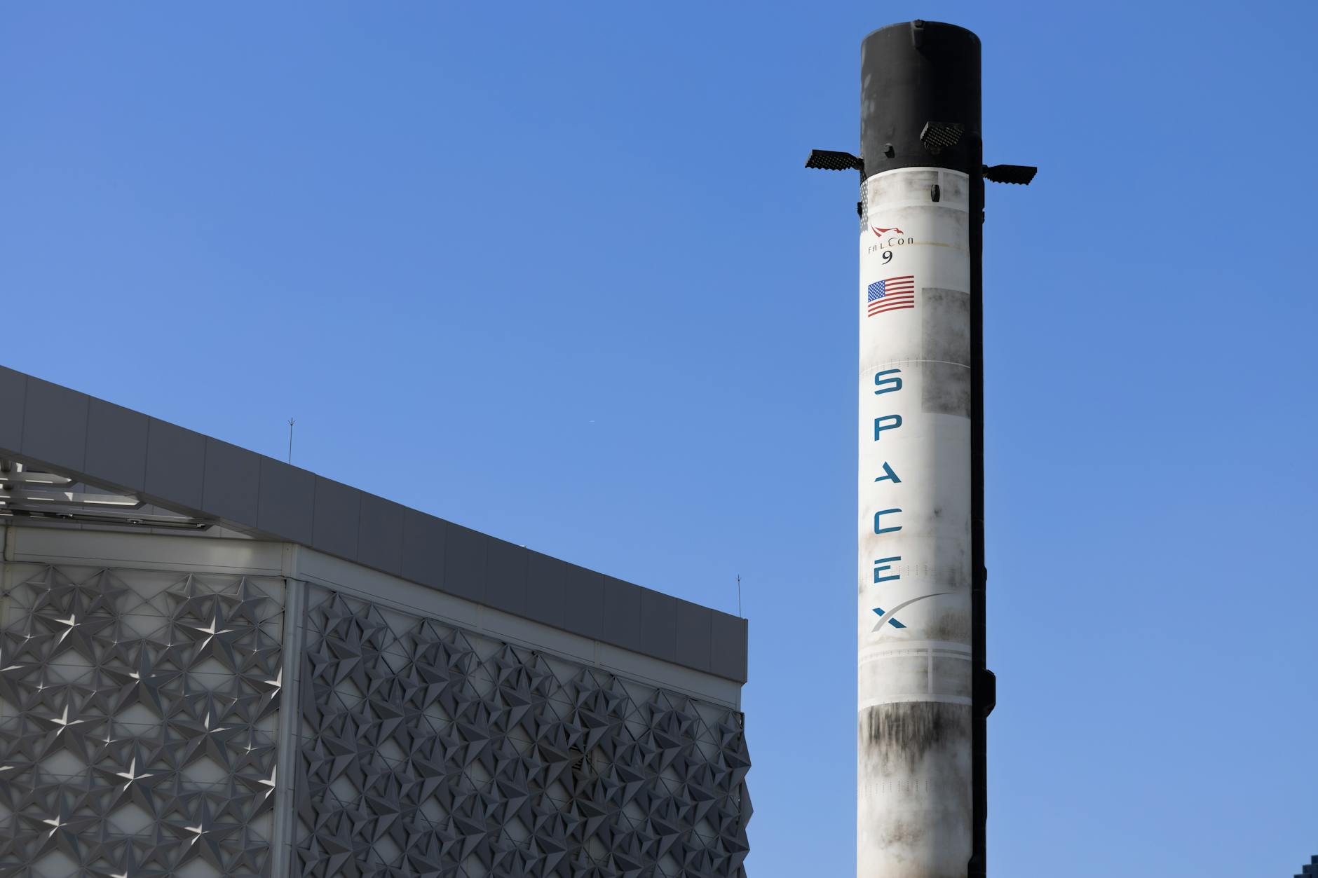 A SpaceX Falcon 9 rocket displayed outdoors against a clear blue sky in Dubai.